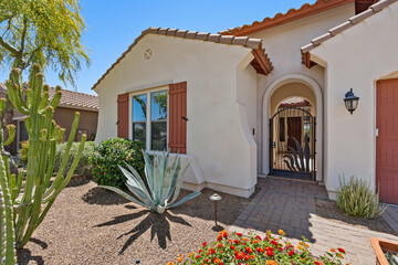 A charming white house featuring red shutters and a cactus placed in front of it