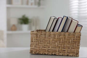 Different books in box on white desk indoors. Space for text