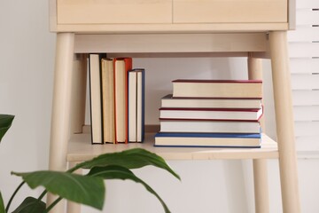 Different books on shelf of nightstand indoors