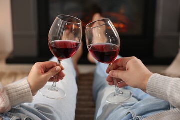 Couple with glasses of wine near fireplace on floor at home, selective focus
