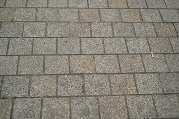 Granite pavement texture with geometric stone pattern. Urban background of grey and beige paving blocks — natural stone surface for architecture, design, and construction concepts.