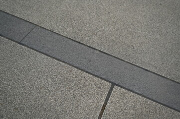 Fototapeta premium Stone pavement with rectangular tiles. Close-up of urban sidewalk surface with textured stone blocks