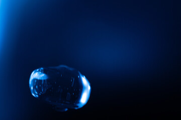 A glowing, translucent blue bubble floats against a dark blue background, with reflections and...