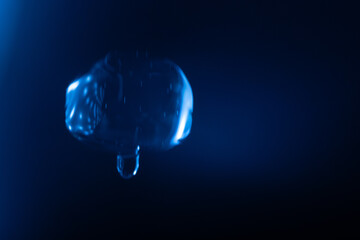 A glowing, translucent blue bubble floats against a dark blue background, with reflections and light streaks creating a futuristic and surreal effect. Includes copy space.