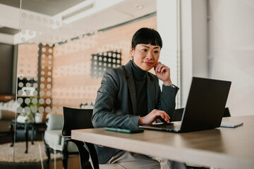 Asian businesswoman working on laptop in modern office