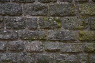 Gray stone wall with moss texture, old masonry background. Natural rough surface, historical architecture detail, and aged stone pattern.