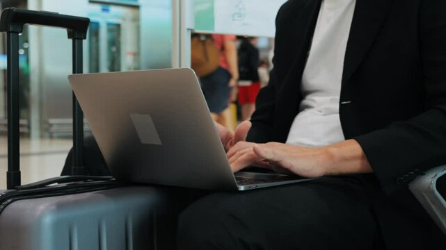 Businessman Uses Laptop, Waiting for a Flight in Airport Terminal or train station, Traveling Entrepreneur Working Online On Computer Sitting in a Boarding Lounge of Airline Hub with Airplanes