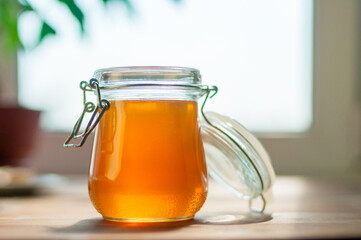 A Clear Glass Jar Filled With Golden Honey Rests on a Wooden Table