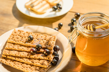 Delicious crackers are served alongside a jar of honey and fresh blueberries, creating a warm, inviting atmosphere perfect for enjoying a healthy snack.