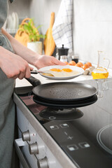 Woman putting tasty fried eggs onto plate in kitchen, closeup