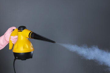 Woman with steam cleaner on grey background, closeup. Space for text