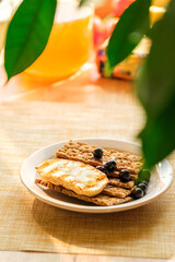 A Plate Holds Crunchy Crackers Topped With Fresh Blueberries, Set in a Vibrant Kitchen Filled With Sunlight and Cheerful Decor