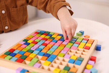 Fototapeta premium Motor skills development. Little boy playing with Times table tray indoors, closeup