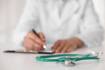Doctor working and stethoscope on table in hospital, selective focus