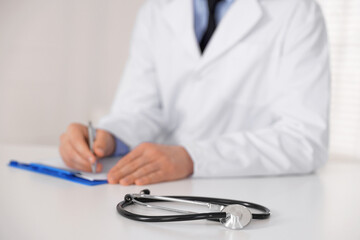 Doctor working and stethoscope on table in hospital, selective focus