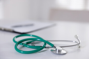 Stethoscope and paperwork on white desk in hospital, selective focus. Space for text