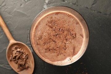 Tasty chocolate milk with shavings on black table, top view
