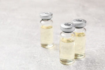 Hepatitis vaccine in glass vials on grey table, closeup. Space for text