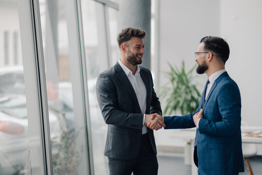 Two businessmen shaking hands in modern office, closing a business deal