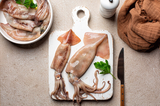 Cooking squid or calamari, or totano, Fresh raw seafood on a wooden cooking board. Top view.