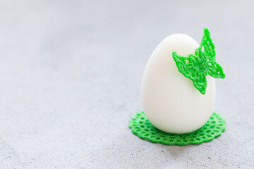 Easter Chocolate cream dessert in the shape of an Easter egg, decorated with green waffle lace decor, with a butterfly and a napkin. Light background. Copy space