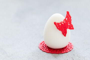 Easter Chocolate cream dessert in the shape of an Easter egg, decorated with red waffle lace decor, with a butterfly and a napkin. Light background. Copy space