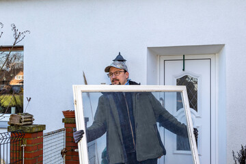 Carpenter removing old window during home renovation for energy efficiency.