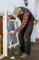 Craftsman applying sealing tape to window frame for thermal insulation during renovation.
