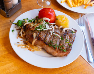 Serving of beef entrecote with vegetables on plate with fries salad on side and glass of wine