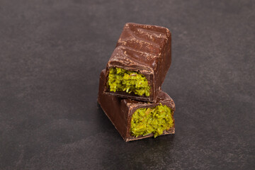 Modern dessert. Dubai chocolate bar with crispy kataifi and pistachio paste. Dark background. Close up