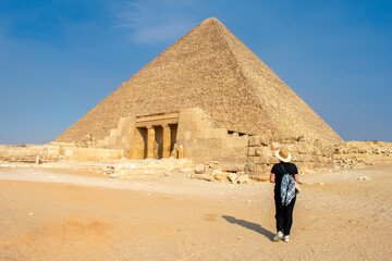 Back view of Young woman taking picture of Great Sphinx and Great Pyramid of Cheops, Cairo, Egypt. Ancient statue of Sphinx, mythical creature with head of man and body of a lion