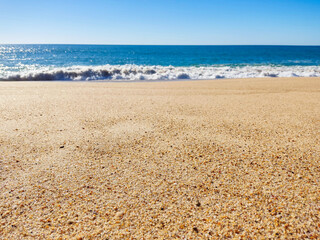 Serene beach scene with golden sand meeting the azure ocean under a clear blue sky. Ideal for travel, relaxation, or summer themes. Promotes tranquility.
