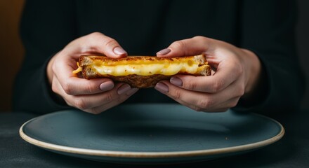 Close-up of grilled cheese sandwich held by female hands over a plate