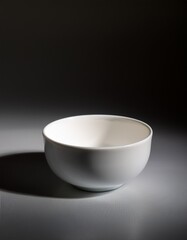 グレーのマットな背景に白い陶器のスープボウルが一つだけ静かに置かれ、光と陰が織りなすやわらかな空間が広がる