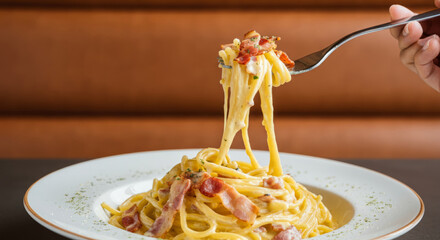 Delicious spaghetti carbonara with bacon and creamy sauce on white plate