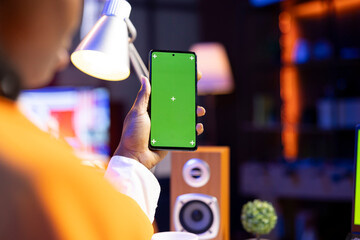 Teenager reading messages on green screen mockup mobile phone, close up shot. Woman in neon lit apartment reading SMS on isolated screen chroma key smartphone, chatting with friends
