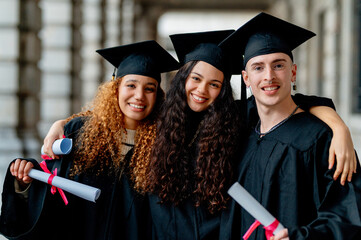 Group of multi ethnic graduating students hugging and smiling at the camera