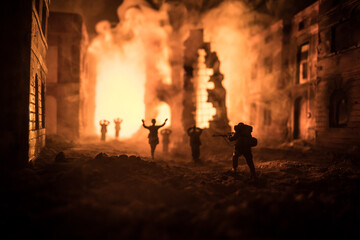 Military silhouettes fighting scene on war fog sky background. A German soldiers raised arms to surrender. Plastic toy soldiers with guns taking prisoner the enemy soldier.