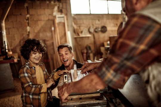 Three male generations working together on a woodworking project in family workshop
