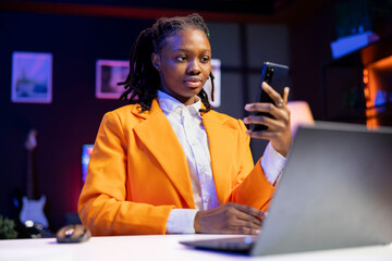 Gen Z teenager scrolling on mobile phone, checking social media feed while at home. African...