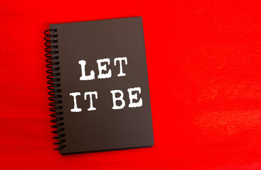 Let it be message written on black notebook page on red background. Conceptual let it be symbol. Copy space.
