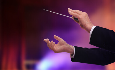 Conductor with baton in concert hall, closeup. Space for text