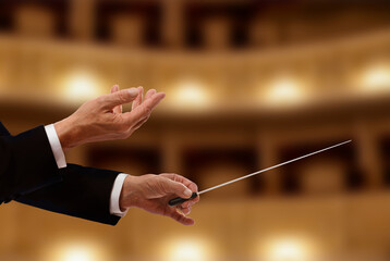Conductor directing orchestra with baton in concert hall, closeup
