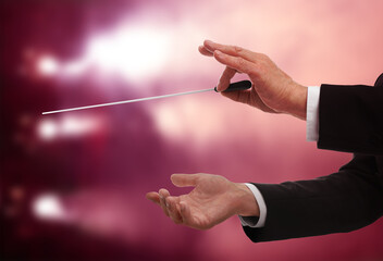 Conductor with baton in concert hall, closeup