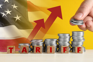 Tariff increase. Man stacking coins near cubes on table, closeup. Flag of USA and arrows