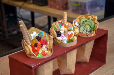 Bubble waffles featuring colorful candy toppings, whipped cream, and savory ingredients like...