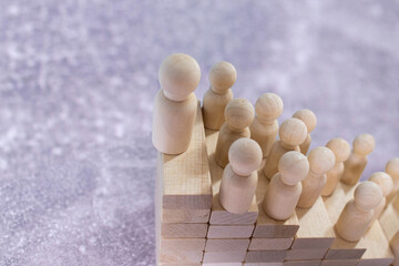 Wooden figures standing on wooden cube stairs.