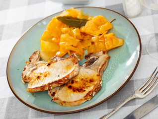 Lunch for one person is served on table - fried meat and stewed vegetables. Roast pork chop is complemented with stewed cabbage, stew of large pieces of cabbage with tomato dressing