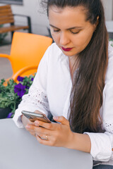 A young pretty woman works in a cafe. She is having a good time in the cafe, drinking coffee and using the phone