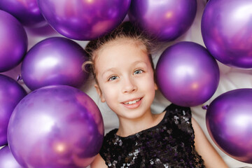 Portrait of little stylish girl with purple balloons on white background. Celebration, birthday, party, childhood concept. Top view